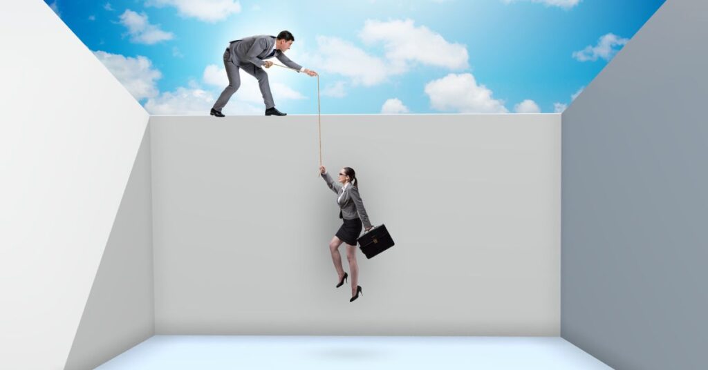 Businesswoman climbing out of a deep, confined space with the help of a businessman pulling her up with a rope, symbolizing escaping from a trapped or difficult situation.