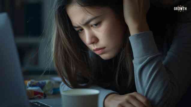 Image of an asian female vibe coding in a dimly lit room with the light on the laptop on her disappointed face.
